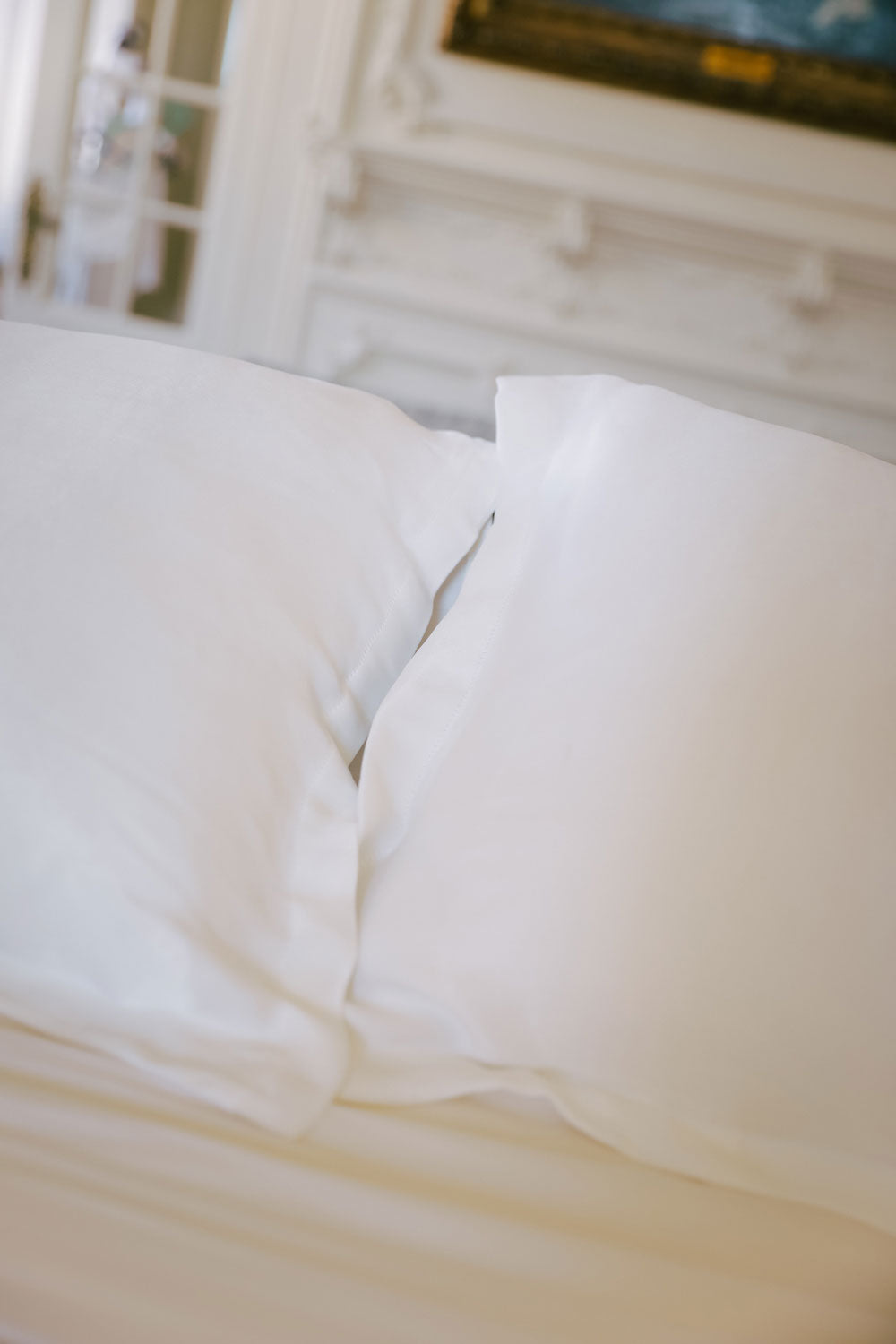 Two white silk pillows on a bed.