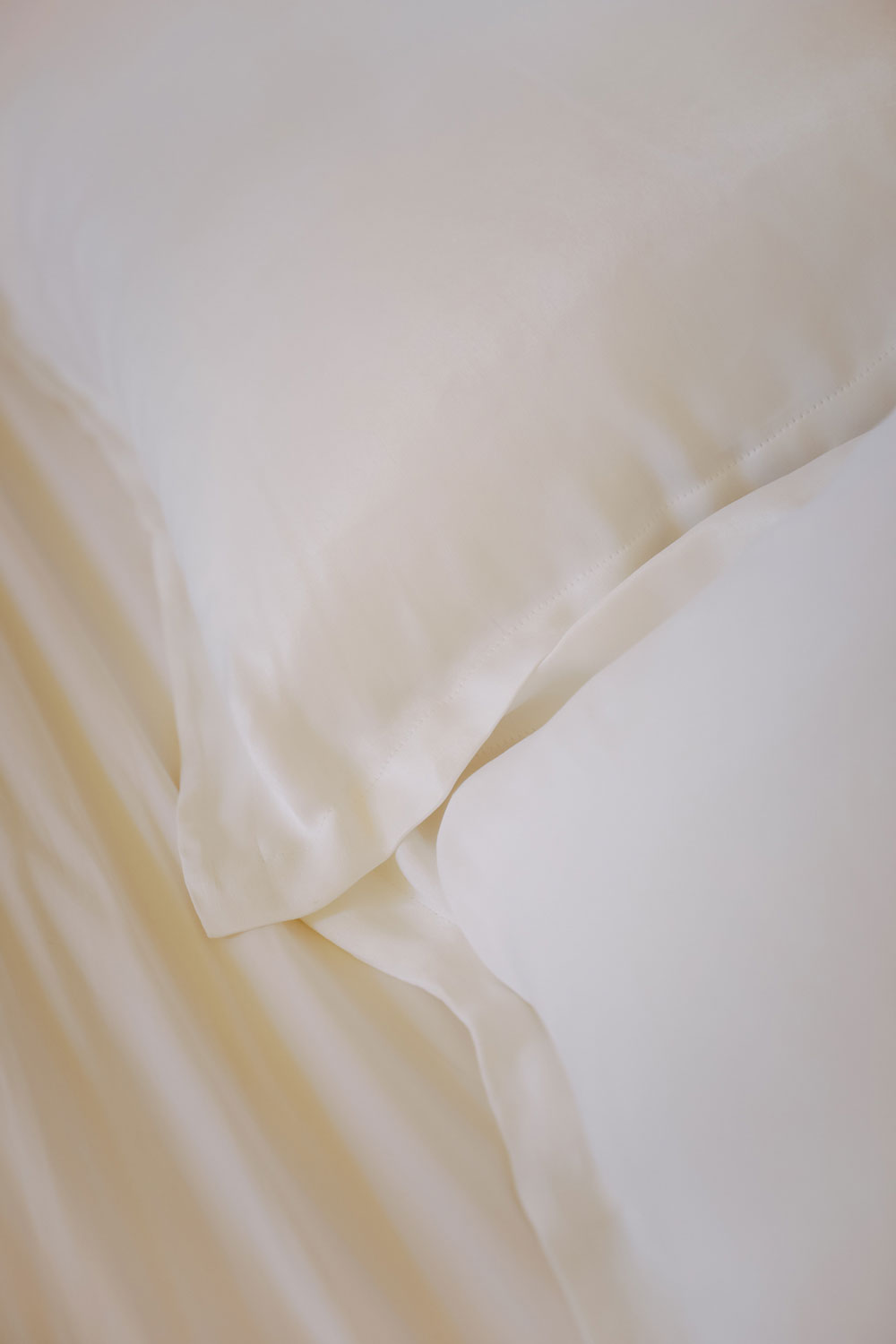 detail of two white silk pillows on a bed.